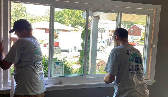 Two people are replacing a window