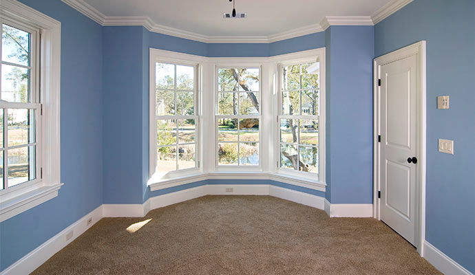 Bright interior room with large bay windows, blue walls, and beige carpet showcasing home remodeling in Bethel Park, PA