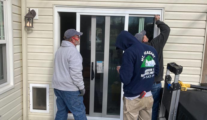 Three people are replacing door
