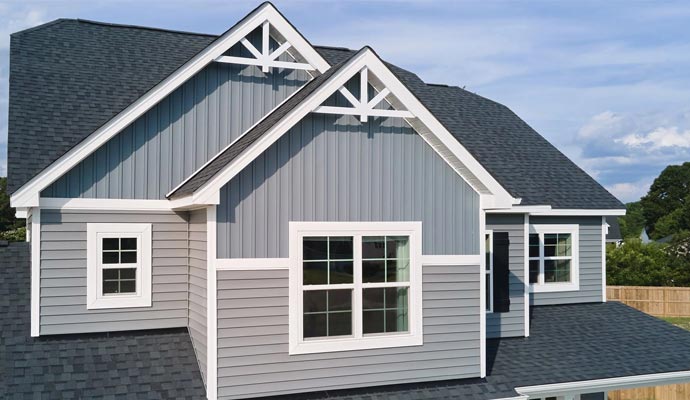 A house exterior featuring Mastic Structure gray vinyl siding with white trim and decorative gables