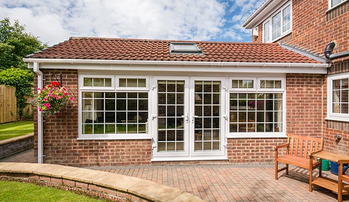 Classic French Doors for Patio Access White uPVC French patio doors with a classic grid pattern, set into a brick home extension and opening onto a brick patio.