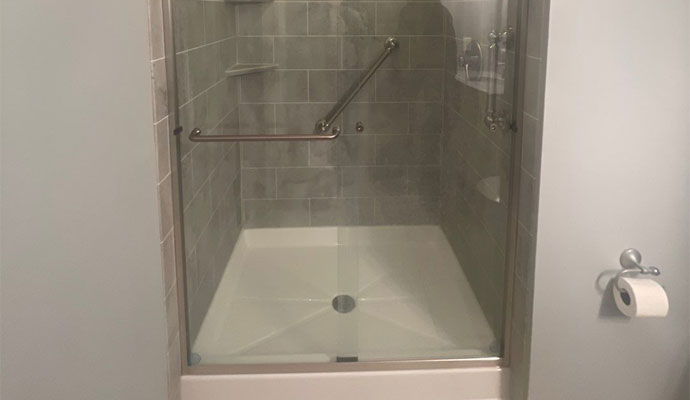 Modern walk-in shower with safety grab bars and glass enclosure